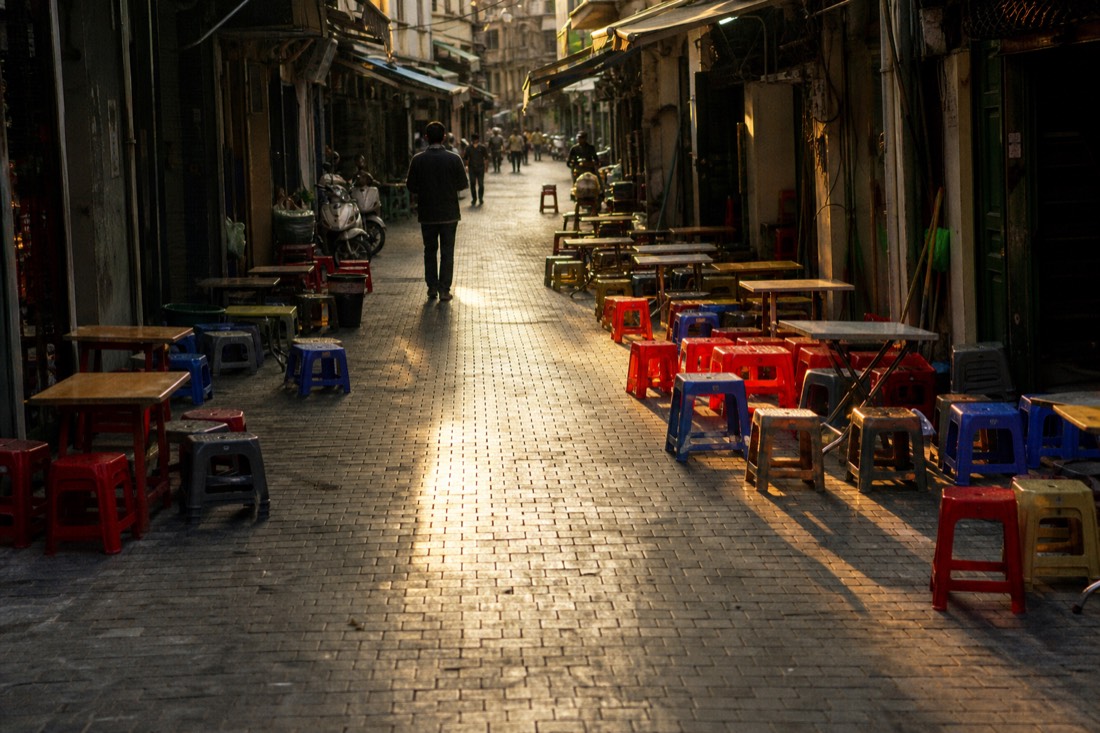 Empty low plastic stools and tables lined up along narrow Ta Hien street just before the evening crowd arrives in Hanoi
