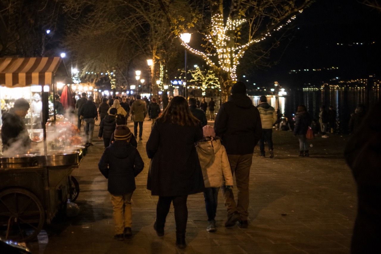 Crowds strolling the car-free Hoan Kiem walking street in Hanoi at night with the lake glowing behind