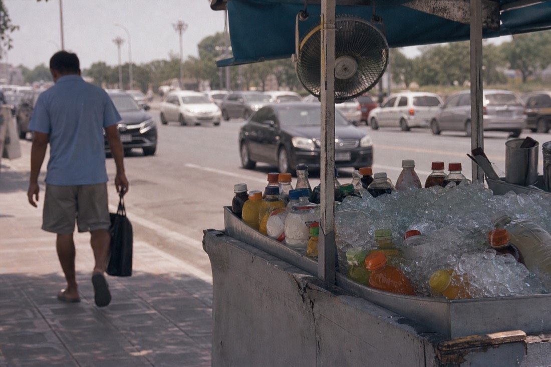 Street vendor cart with fans blowing on stacked ice and cold drinks under harsh midday summer sun