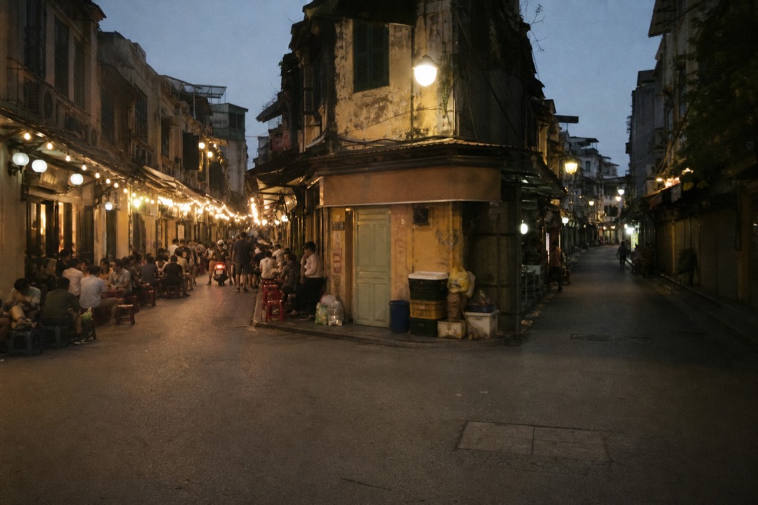 Two Hanoi Old Quarter alleys branching at dusk, one busy with diners, one quiet