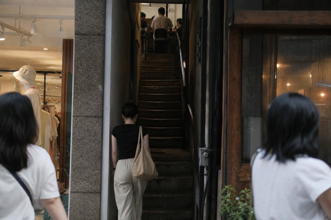 Narrow staircase corridor leading up to a hidden second-floor Hanoi coffee shop