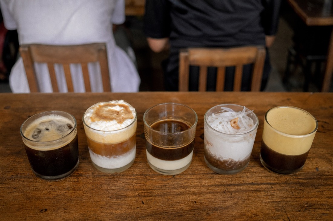 Row of different Vietnamese coffee drinks including egg coffee and coconut coffee lined up for a tasting