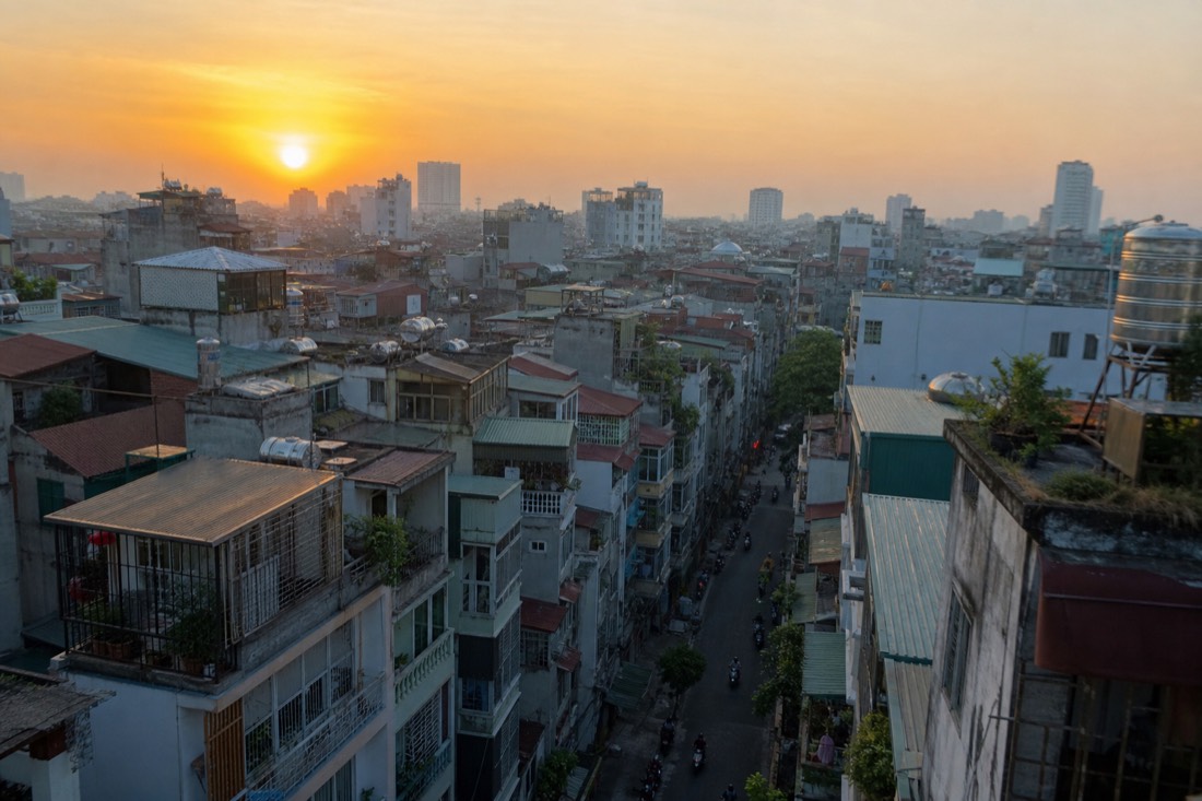 View over Hanoi Old Quarter rooftops and narrow streets at golden hour sunrise