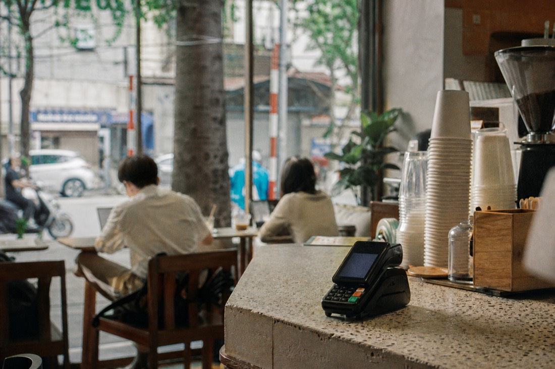 Modern Hanoi cafe counter with a card payment terminal beside coffee cups