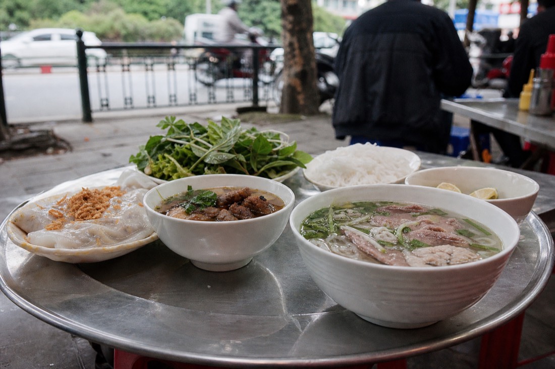 Small tasting bowls of banh cuon, bun cha and pho arranged together on a shared tray