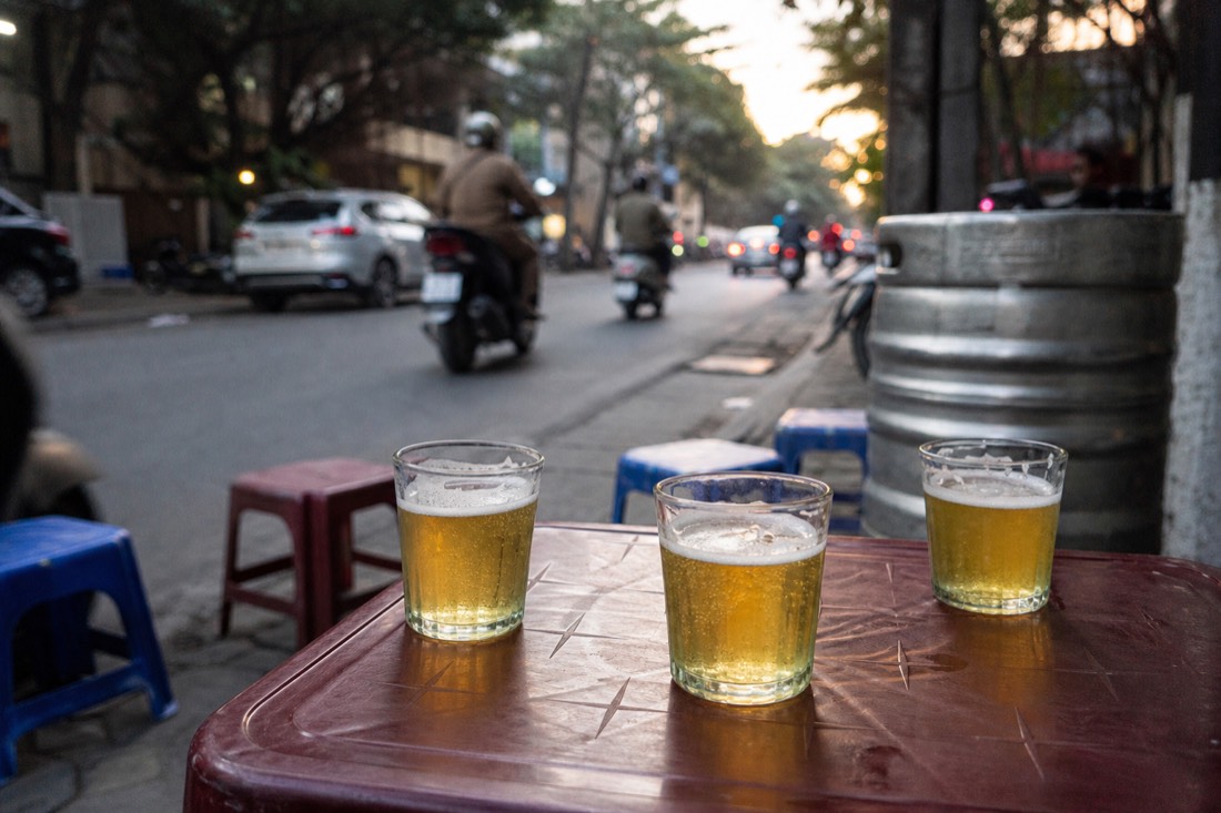 Small glasses of bia hoi fresh beer on a low table at a Hanoi street corner in the evening