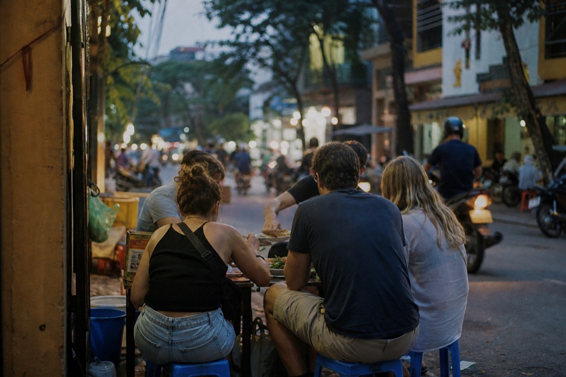 Small group of diners sharing a table of street food dishes with a local guide in Hanoi
