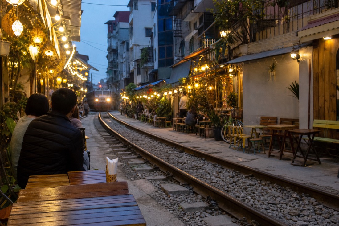 Cafe tables along Hanoi's Train Street corridor lit for the evening ahead of a train