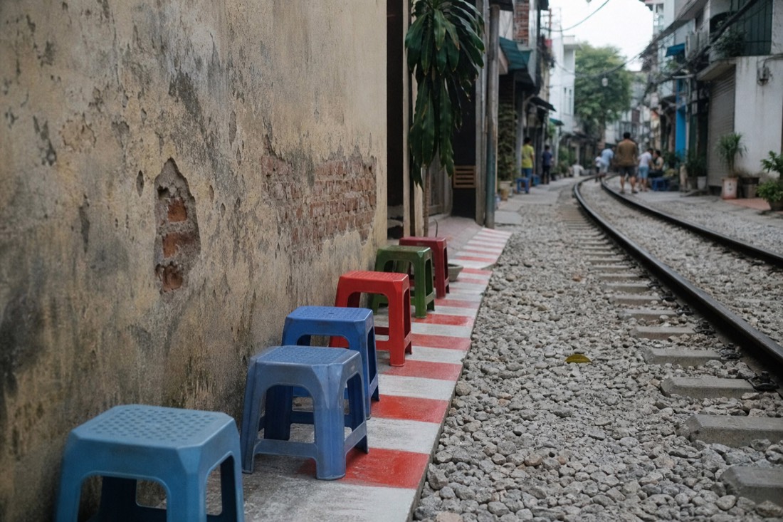 Cafe stools pushed back against the wall behind a marked safety line in Hanoi's Train Street corridor