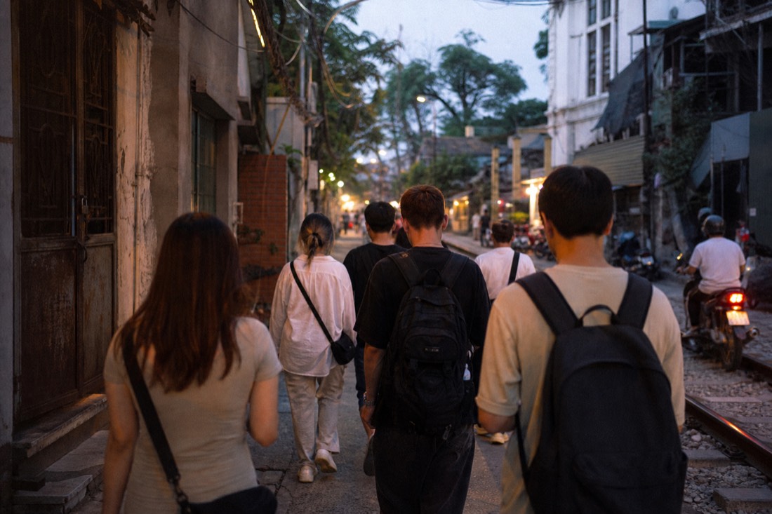 Guide leading a small group toward the Train Street barrier in the evening in Hanoi
