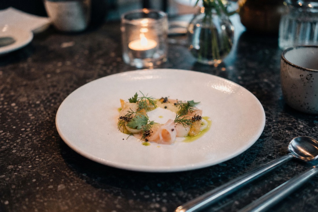 Elegantly plated tasting course on a dark table at an upscale Hanoi restaurant with candlelight