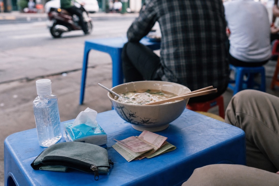 Small travel kit of hand sanitizer, tissues and small dong notes laid out on a low stool table