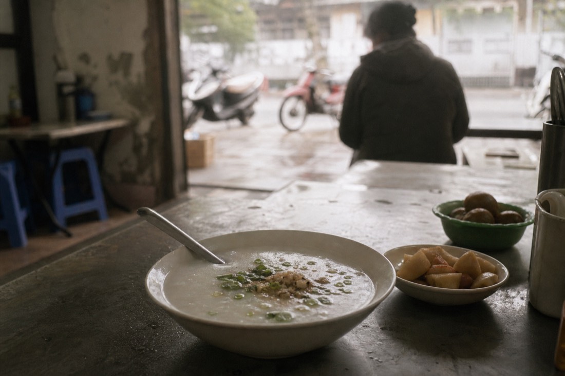 Simple bowl of plain rice porridge on a table in a quiet Hanoi eatery