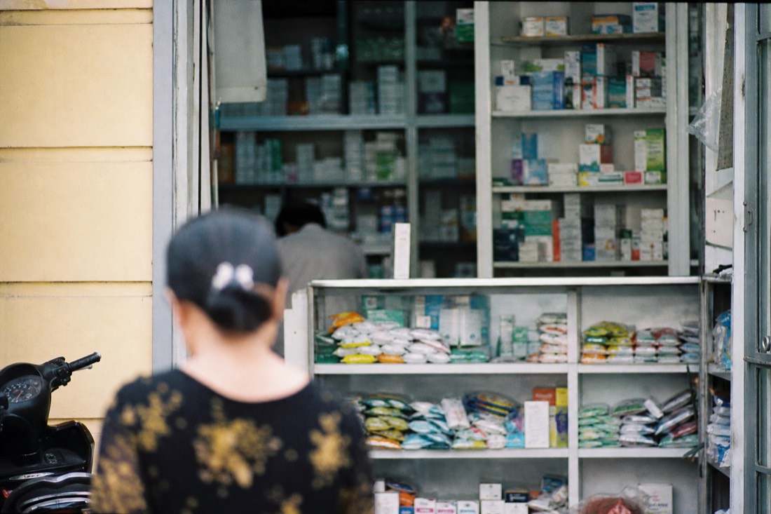 Shelves of medicine and rehydration salt packets inside a small Hanoi pharmacy