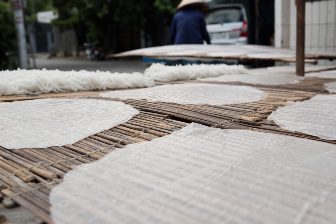 Fresh rice noodles and rice paper sheets drying on bamboo racks in a Hanoi kitchen