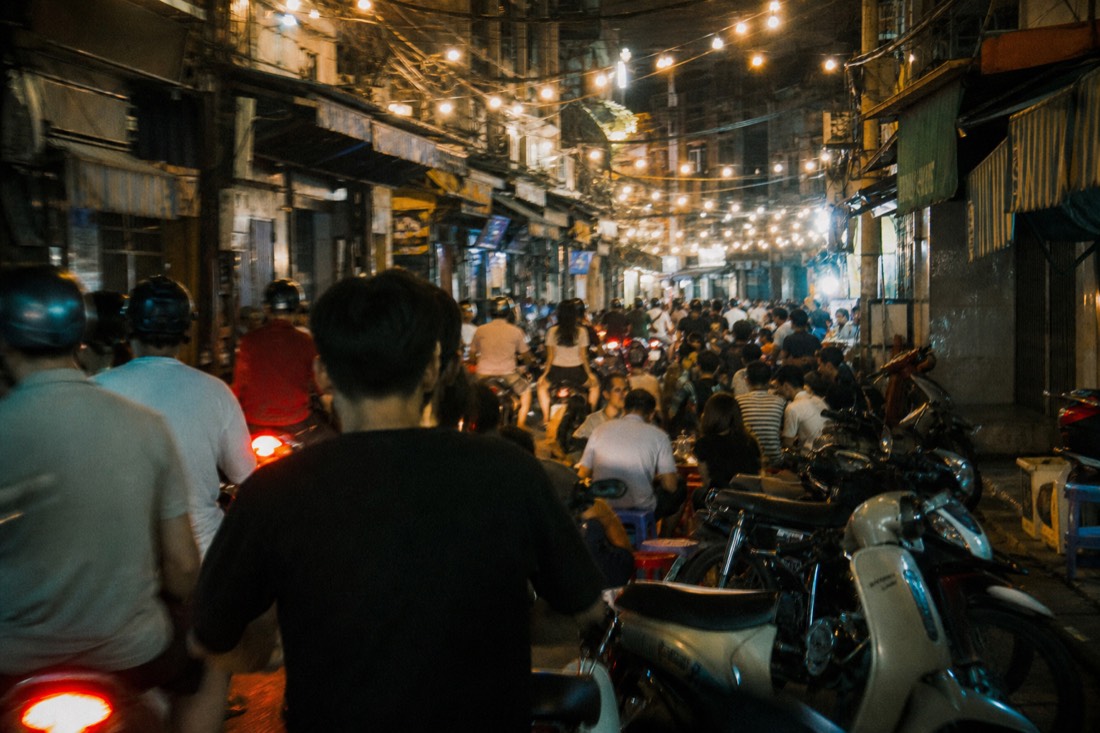 Densely packed Old Quarter street at night full of motorbikes and glowing string lights