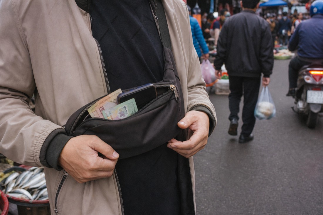 Small Vietnamese dong notes and a phone in a crossbody bag on a busy Hanoi street