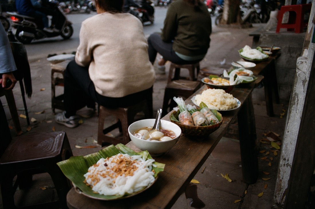 Ten small dishes of Hanoi street food samples arranged in a row for tasting