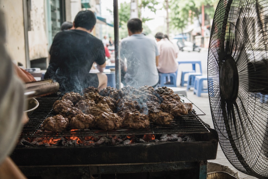 Charcoal grill loaded with bun cha pork patties at a Hanoi lunch stall