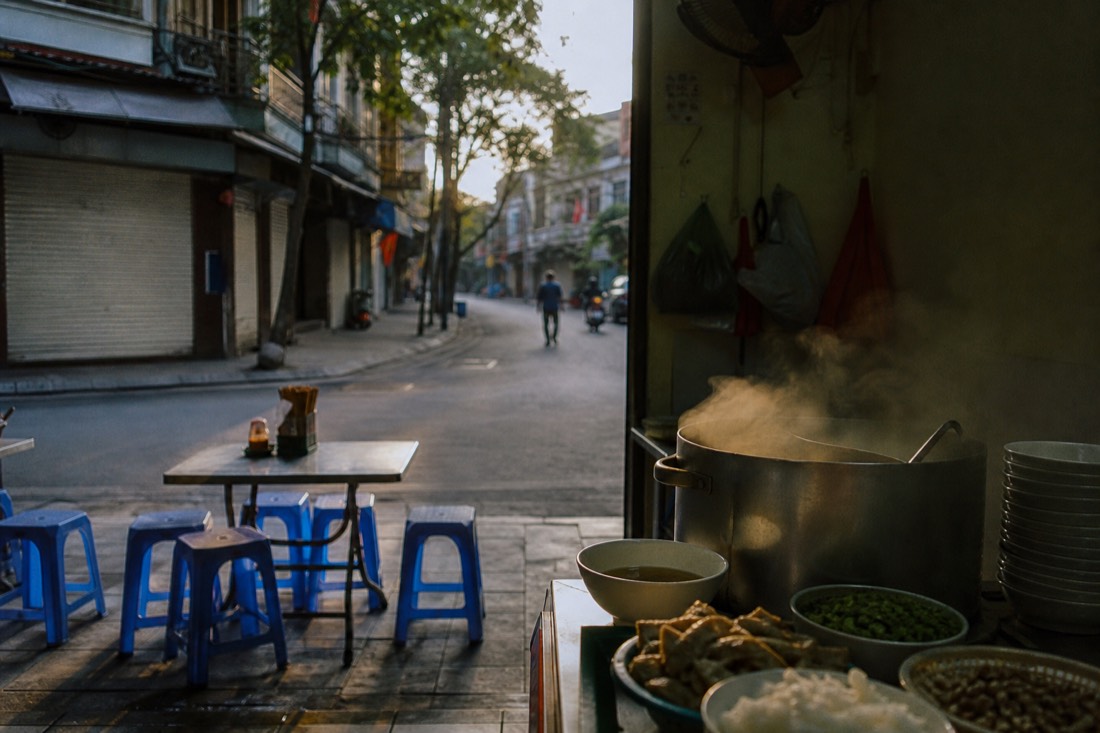 Breakfast pho stall opening at dawn on a quiet Hanoi Old Quarter street