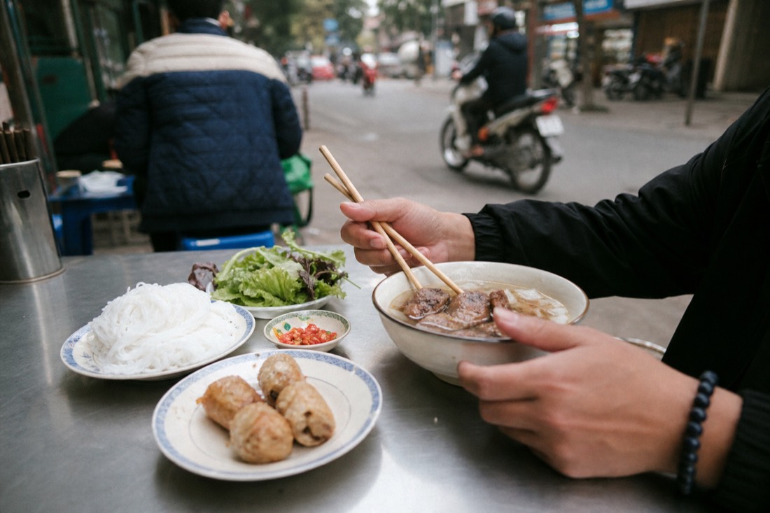 Solo diner eating a bowl of bun cha at a Hanoi restaurant table