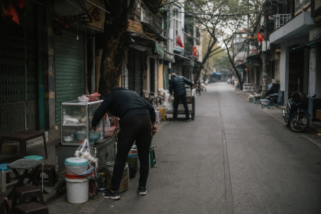 Quiet early-morning Old Quarter street with vendors setting up stalls before the crowds arrive